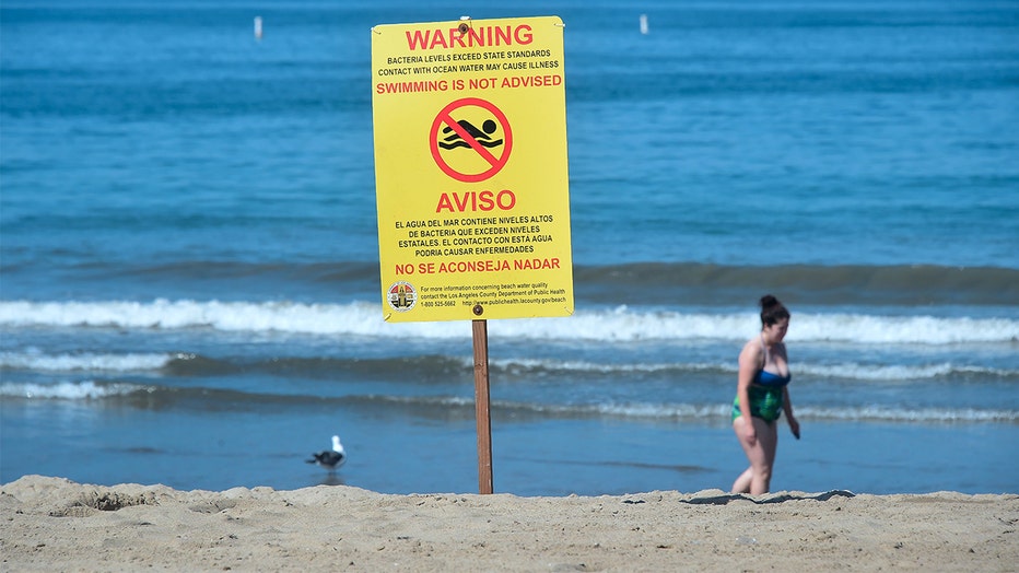 A warning sign is posted advising against swimming in the waters off Santa Monica State Beach beside Santa Monica Pier on World Oceans Day on June 8, 2018 in Santa Monica, California. 