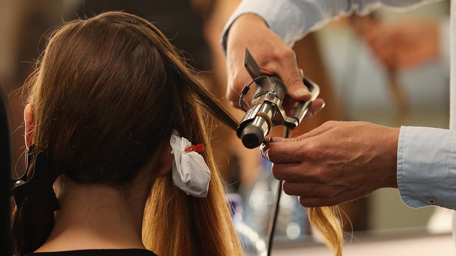 FILE: A model gets her hair curled. In extremely rare cases, hair grooming can cause seizure-like reactions in children.