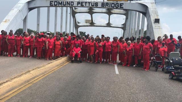 100 'Ladies in Red' cross historic bridge in Selma, Alabama on civil rights tour