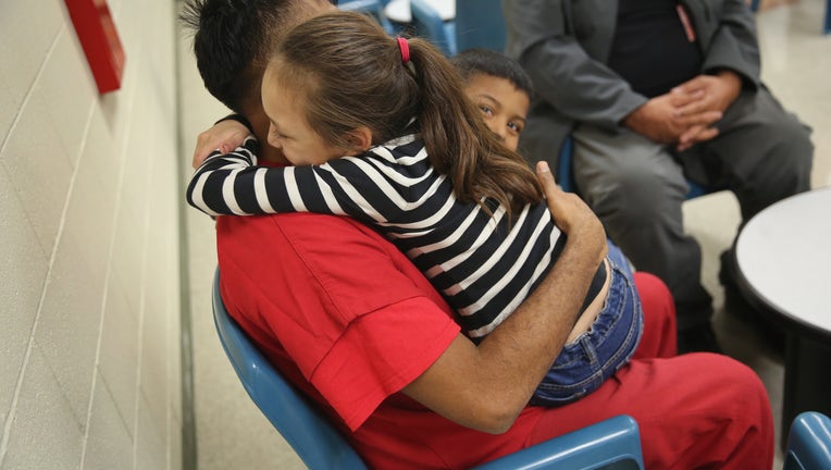 ADELANTO, CA - NOVEMBER 15: An immigrant detainee holds his children during a family visitation visit at the Adelanto Detention Facility on November 15, 2013 in Adelanto, California. The facility, the largest and newest Immigration and Customs Enforcement (ICE), detention center in California, houses an average of 1,100 immigrants in custody pending a decision in their immigration cases or awaiting deportation. The average stay for a detainee is 29 days. The facility is managed by the private GEO Group. ICE detains an average of 33,000 undocumented immigrants in more than 400 facilities nationwide.