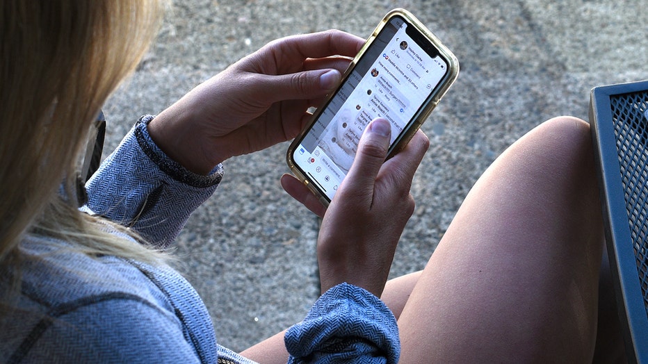 A young woman scrolls through Facebook on her phone as she sits outside a coffee shop in Jacksonville, Oregon. Hundreds of millions of phone numbers linked to user accounts were discovered in an online database.