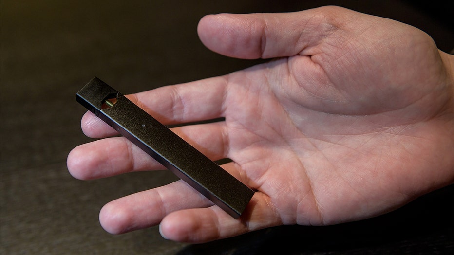 FILE - A man holds an e-cigarette of the manufacturer 