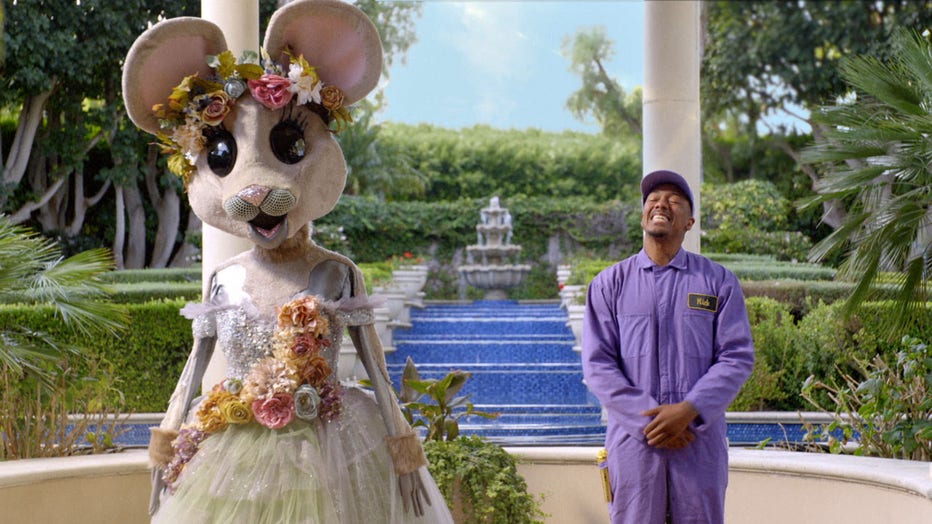 “The Masked Singer” host Nick Cannon is pictured delivering a mouse costume to a mystery celebrity in a teaser clip of season 3. (Photo credit: FOX)