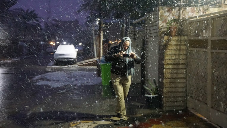 An Iraqi man takes pictures with his smart phone during snow fall early on February 11, 2020 in Baghdad, as the Iraqi capital woke up covered in a thin layer of fresh snow, an extremely rare phenomenon for one of the world's hottest countries. - The last recorded snowfall in the city was in 2008, but it was a quick and mostly slushy affair -- and prior to that, it had been a century since Baghdad saw any flakes. (Photo by SABAH ARAR / AFP) (Photo by SABAH ARAR/AFP via Getty Images)