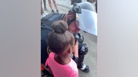 Police officer comforts crying little girl who asked 'are you gonna shoot us?' during protest