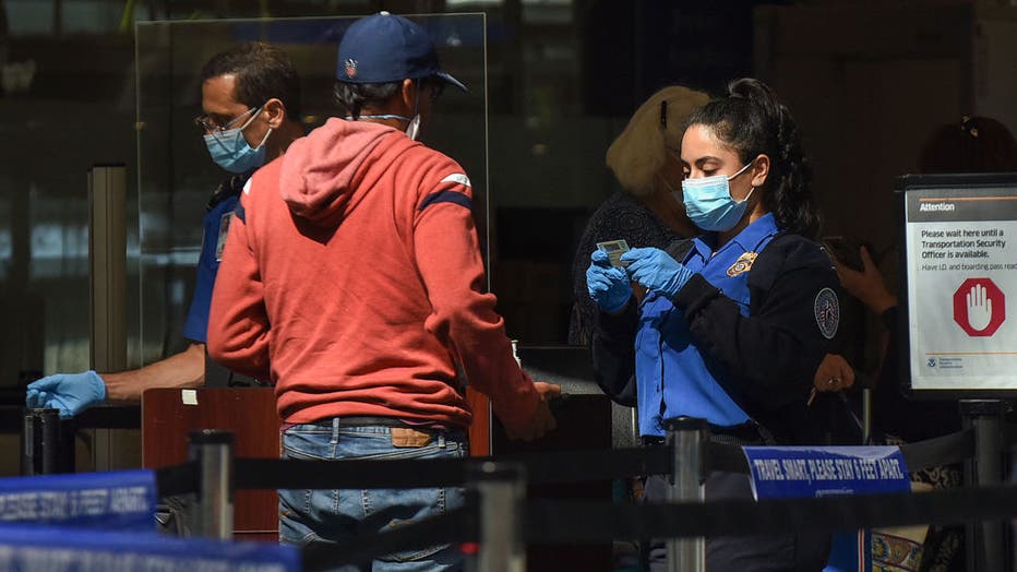 A TSA officer checks a man's ID at a screening checkpoint at