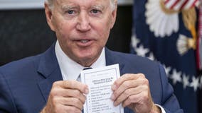 Biden holds notes that read 'YOU enter the Roosevelt Room,' 'YOU take YOUR seat'