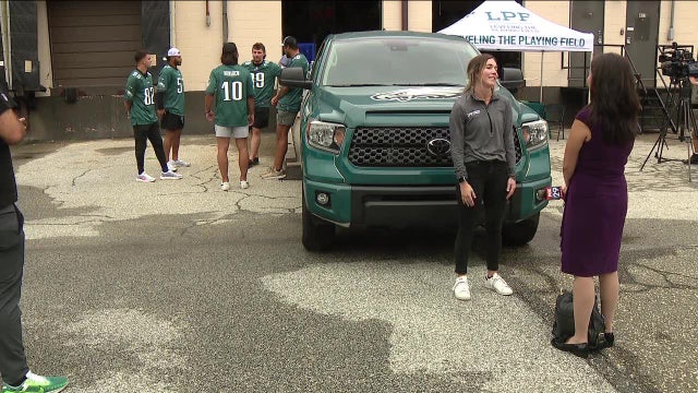 Eagles players help unload and redistribute used sporting goods to children in need