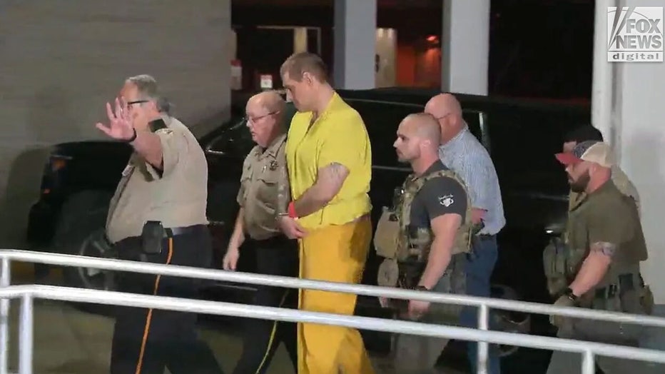 Casey-White-escorted-by-police.jpg
