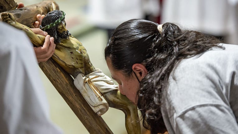FILE - A woman kisses a crucifix of Jesus as she and the church celebrate the Roman Catholic Holiday of Good Friday at the church of St. Rose of Lima Parish in Chelsea, Massachusetts, on April 15, 2022. (Photo by Joseph Prezioso/Anadolu Agency via Getty Images)