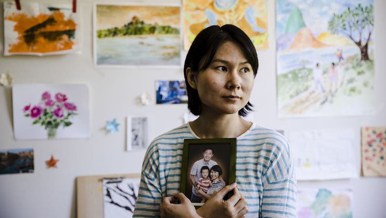 Hua Qu, the wife of detained Chinese-American Xiyue Wang, poses for a photograph with a portrait of her family in Princeton, New Jersey.