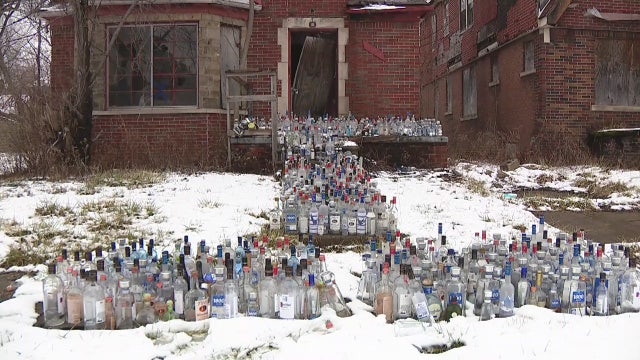 Family honors late relatives with empty liquor bottles outside abandoned house