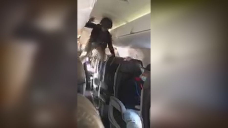 In this screen still from the video, the woman can be seen climbing on airplane seats.