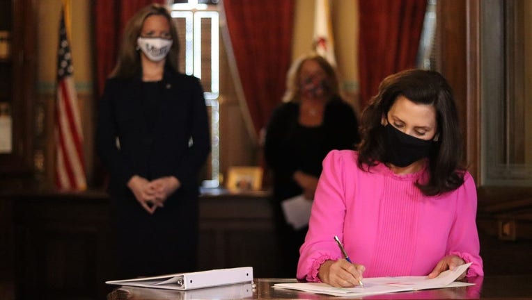 Gov. Gretchen Whitmer sits at a desk signing Senate Bill 757 into law.