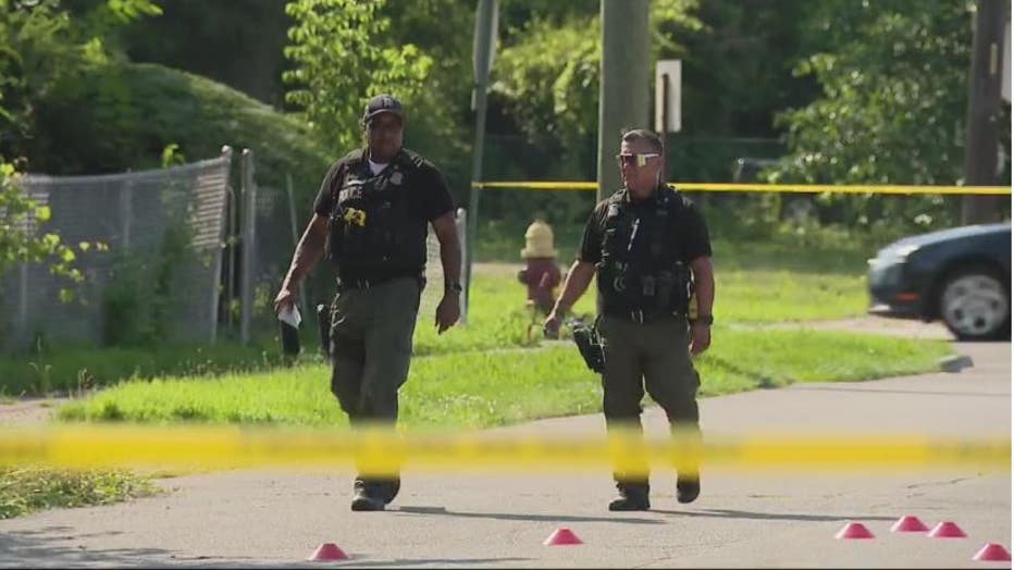 Detroit police officers walk amongst evidence markers of a fatal shooting at Bassett and Francis.