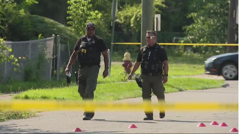 Detroit police officers walk amongst evidence markers of a fatal shooting at Bassett and Francis.