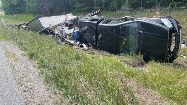Truck pulling camper flips along I-75 in northern Michigan after tire blowout