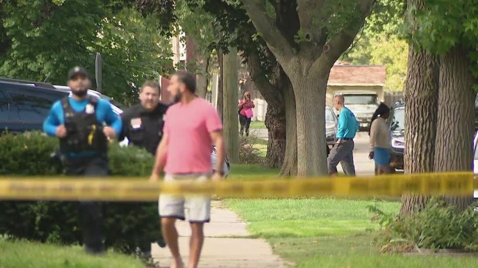 Police scramble behind a bystander near the scene of a shooting in Dearborn Heights Monday.