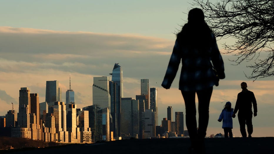 FILE - The sun sets on the skyline of midtown Manhattan and the One World Trade Center in New York City as people walk along the Hudson River on March 17, 2024, in Edgewater, New Jersey. (Photo by Gary Hershorn/Getty Images)