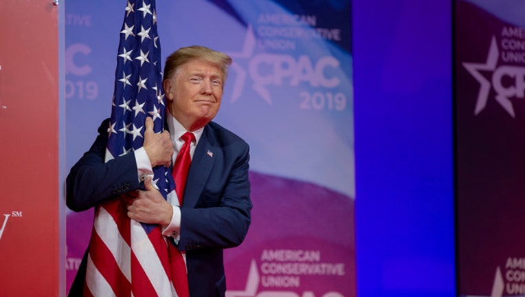 7ea0c705-GETTY Trump hugging a flag at CPAC on March 2, 2019