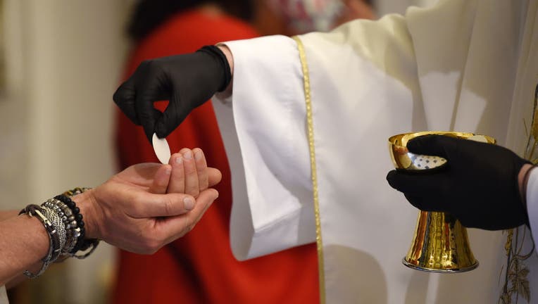 Priest Felice Moliterno gives communion to churchgoers during a mass at Santa Lucia church on May 18, 2020 in Salerno, Italy. 