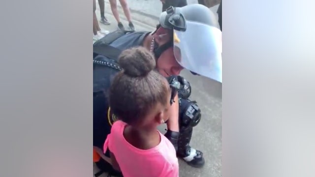 Police officer comforts crying little girl who asked 'are you gonna shoot us?' during protest