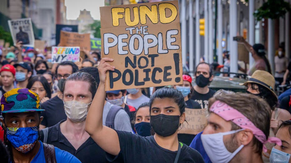 05b646b0-A participant holding a Defund Police sign at the protest.