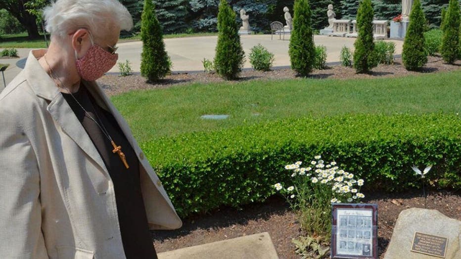 Local-minister-Sr.-Mary-Andrew-Budinski-looks-at-the-memorial-to-remember-the-12-sisters-who-died-in-one-month-from-COVID-19-that-sits-in-the-gardens-outside-the-Felician-Sisters-convent-in-Livonia-Michigan..jpg
