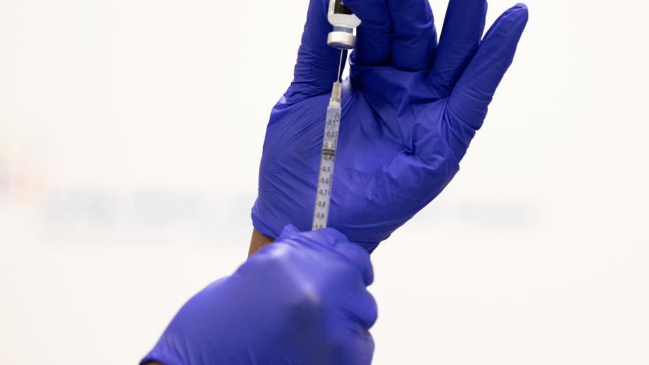 Close-up of glove hands of nurse holding Covid booster vaccine