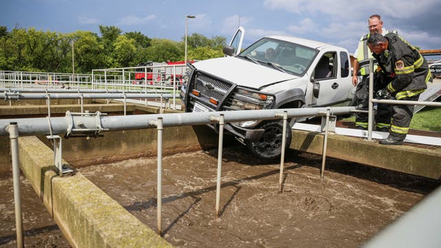 Pickup truck left dangling over wastewater tank after suburban crash, officials say