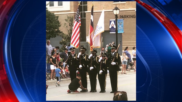 Boy ties shoe of Honor Guard member taking part in Arlington 4th of July parade