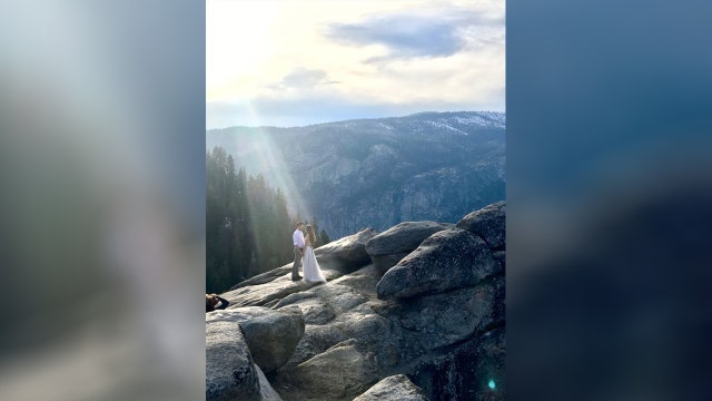 Woman searching for couple after capturing beam of light shining down during engagement photo shoot