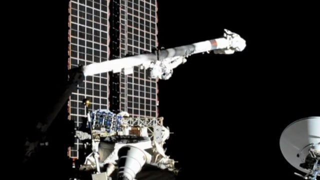 Spacewalking astronauts cutting into cosmic ray detector