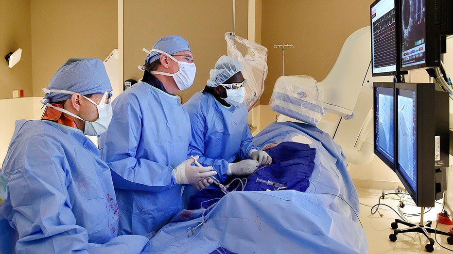 Kenneth Huber, middle, an interventional cardiologist with Saint Luke's Mid America Heart Institute, deploys a coronary stent through the femoral artery of a patient with a blocked artery on November 25, 2015. A new, federally funded study found that many of heart surgeries in non-emergency cases are unnecessary or premature.