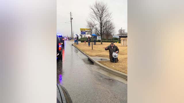 Photo shows stranger kneeling in rain during procession of fallen police officer