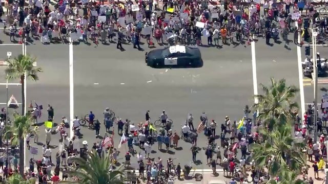 Crowd fails to social distance while protesting in Huntington Beach over pandemic restrictions