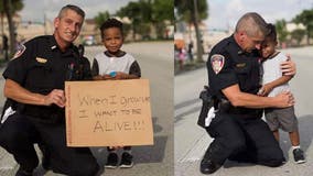 Florida police officer embraces young protester with 'when I grow up, I want to be alive' sign
