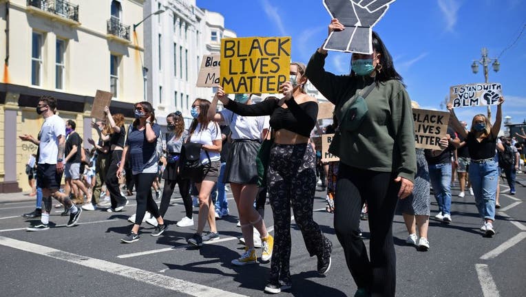 Protesters hold up placards as they march along the seafront in support of the Black Lives Matter movement at a protest action in England on June 13, 2020, in the aftermath of the death of unarmed black man George Floyd in police custody in the US.