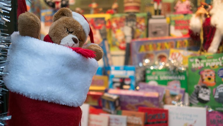 Teddy bear in stocking in front of Christmas gifts.