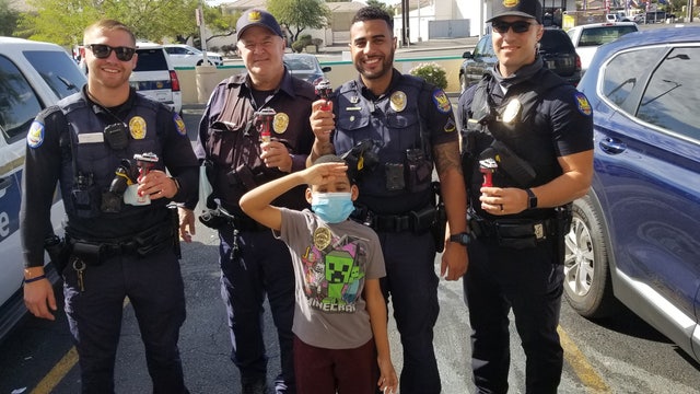 Boy gifts officers candy with toy police cars on top to show appreciation
