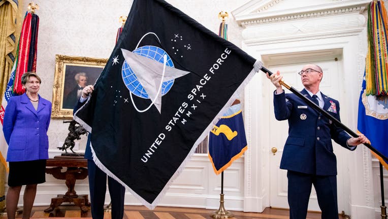 Chief Master Sgt. Roger Towberman (R), Space Force and Command Senior Enlisted Leader and CMSgt Roger Towberman (L), with Secretary of the Air Force Barbara Barrett present US President Donald Trump with the official flag of the United States Space Force