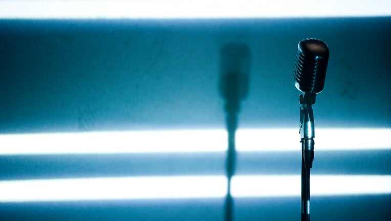A microphone backlit on a stage (Photo by Universal Images Group via Getty Images)