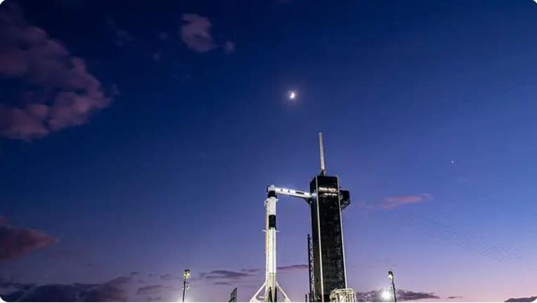 A SpaceX Falcon 9 rocket on Kennedy Space Center launchpad 39A with Jupiter, Saturn, the Moon, above the rocket and Dragon. (SpaceX)