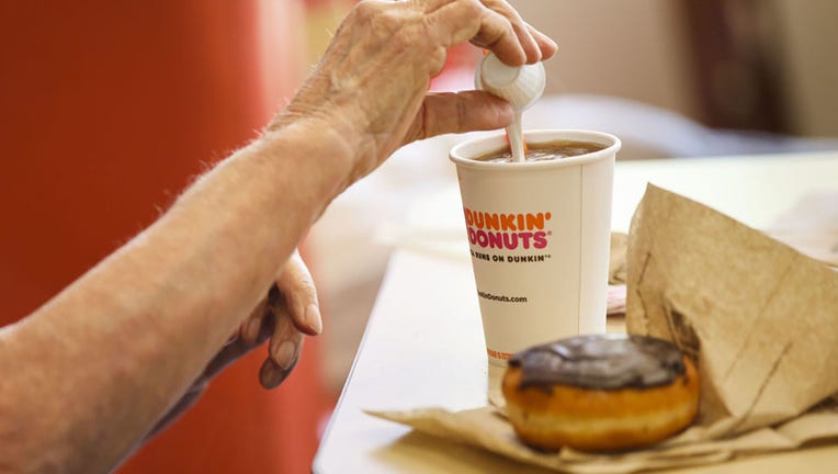 FILE - A customer pours creamer into a cup of coffee at a Dunkin Donuts Inc. location in Los Angeles, California, on Sept. 6, 2017. Photographer: Patrick T. Fallon/Bloomberg via Getty Images