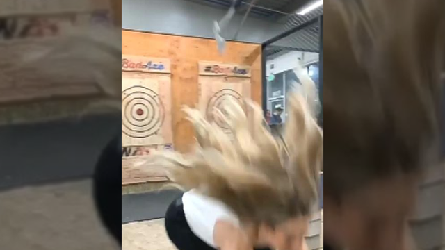 Woman at indoor entertainment center dodges flying ax in viral video