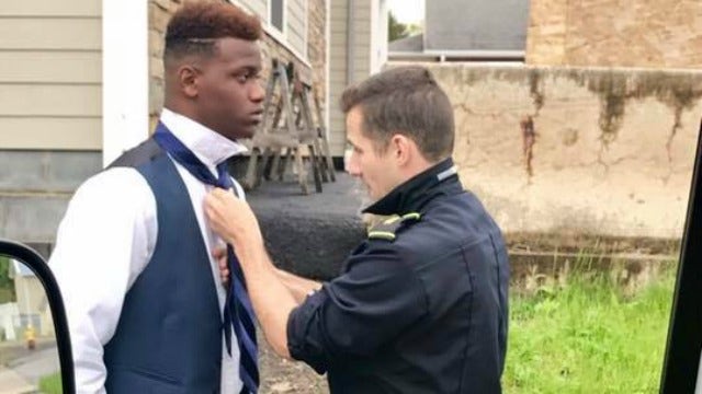 Paramedic helps teen tie his tie before prom