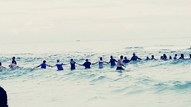 Florida beachgoers form human chain to rescue family in water