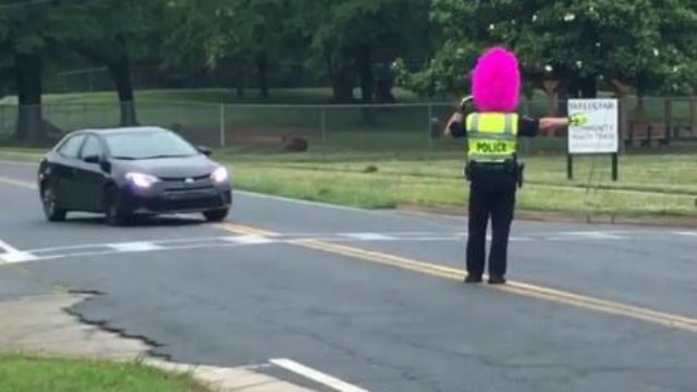 Officer directs traffic in purple wig after losing bet to student