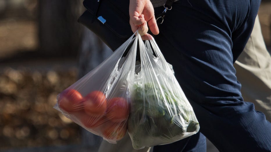 A shopper is seen carrying vegetables in grocery bags in a file image. (Photo by Sergei MalgavkoTASS via Getty Images)