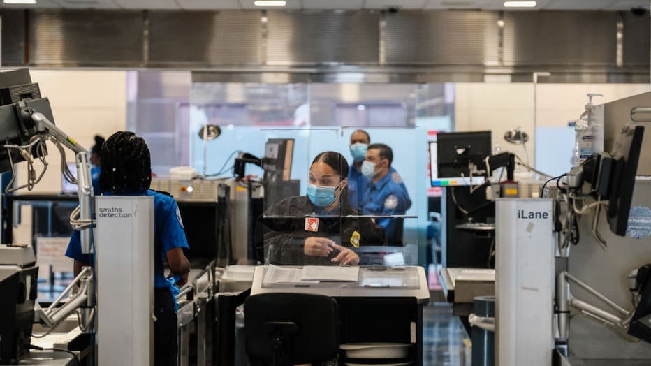 FILE - TSA agents work at a security checkpoint at the Ronald Reagan National Airport on July 22, 2020.